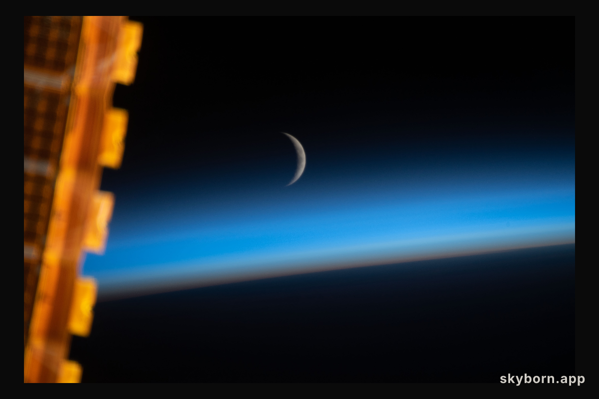 The waxing crescent moon is photographed just above Earth's limb and the bluish hue of the atmosphere at the beginning