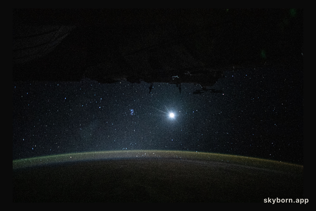 Earth's atmospheric glow, highlighted by the Moon and a starry orbital nighttime background, are pictured