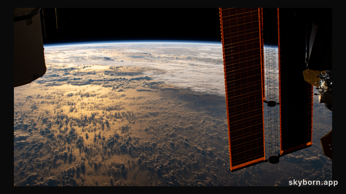 The International Space Station orbits 267 miles above the Earth as the Sun's glint beams over the Philippine Sea