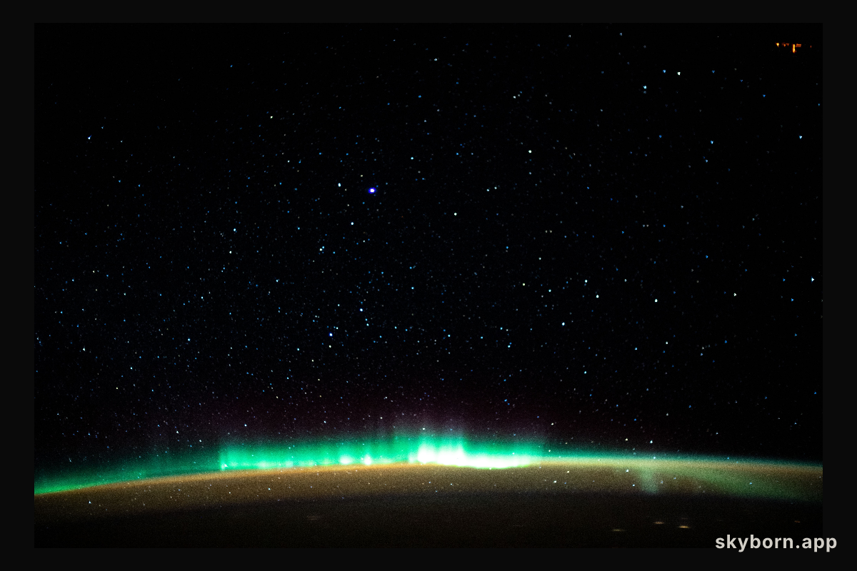An aurora blankets the Earth beneath a celestial night sky as the International Space Station orbited 261 miles