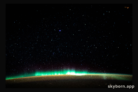 An aurora blankets the Earth beneath a celestial night sky as the International Space Station orbited 261 miles