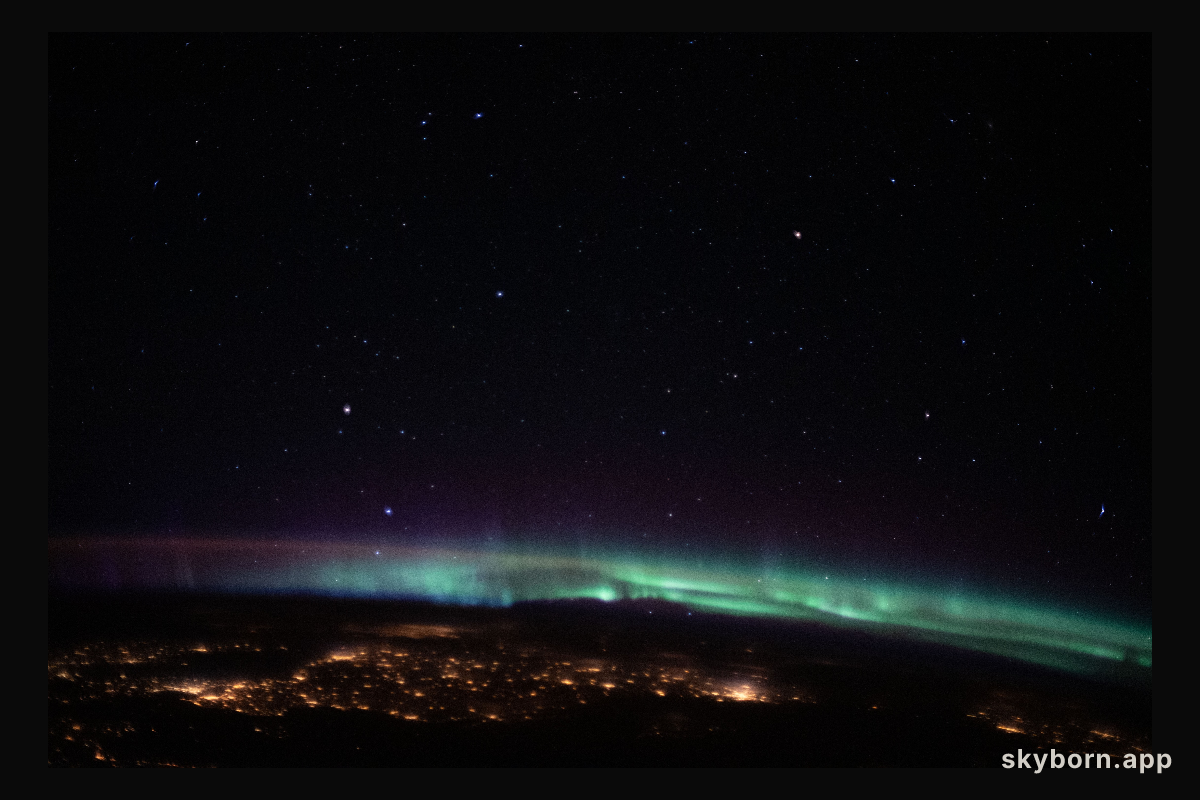 The city lights of northeastern Europe sparkle beneath an aurora and a starry sky as the International Space Station