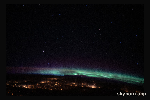 The city lights of northeastern Europe sparkle beneath an aurora and a starry sky as the International Space Station