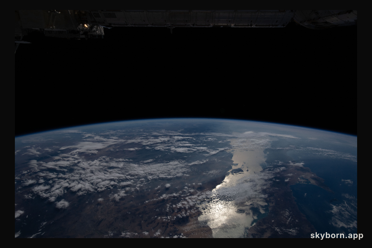 The Earth's limb, or horizon, with the Sun's glint beaming off the Gulf of California, is pictured as the International