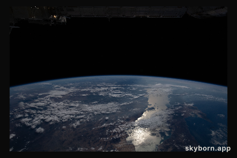 The Earth's limb, or horizon, with the Sun's glint beaming off the Gulf of California, is pictured as the International