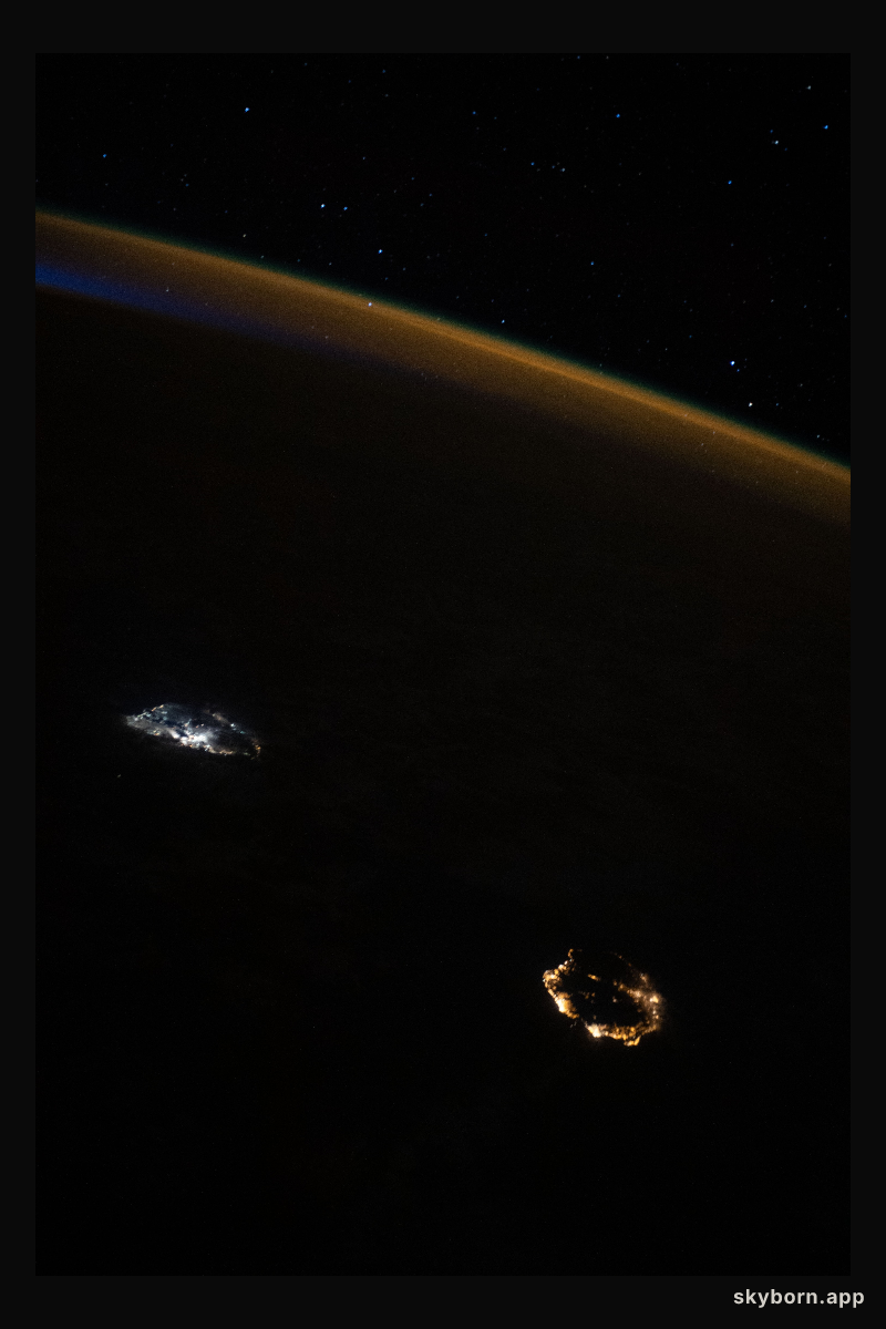 A starry sky, an atmospheric glow and the night lights of the island nation of Mauritius (center left) and Réunion