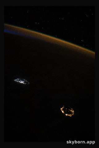 A starry sky, an atmospheric glow and the night lights of the island nation of Mauritius (center left) and Réunion