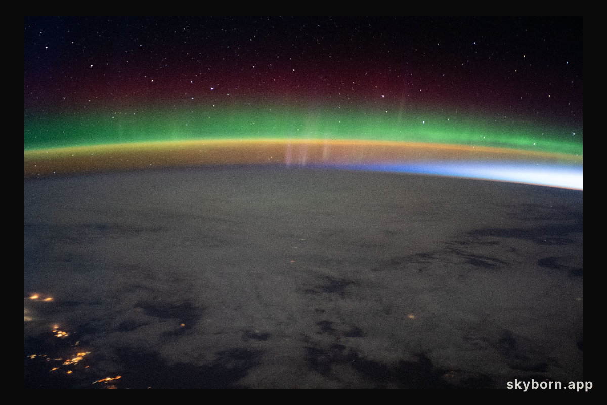 A bright aurora crowns Earth's horizon beneath a starry sky as the International Space Station flew into an orbital