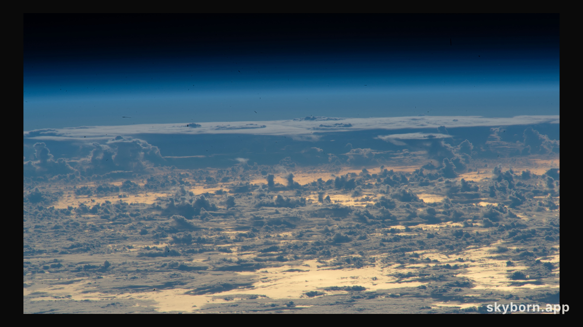 Clouds protrude above the north Atlantic Ocean, with the Sun's glint beaming off the golden-hued waters, in this