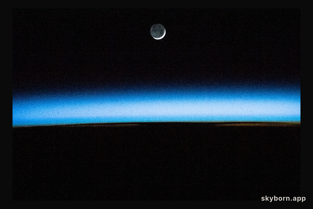The waxing crescent Moon is pictured above Earth's atmosphere illuminated by an orbital sunset as the International