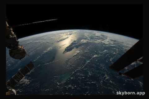 The sun's glint beams across the Caribbean Sea and the Atlantic Ocean highlighting Cuba and Haiti in this photograph