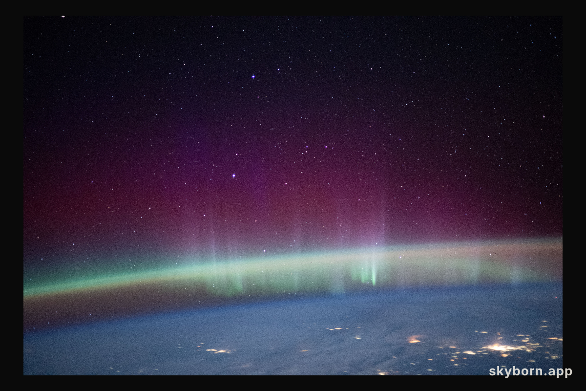 An aurora intersects Earth's airglow beneath a starry sky in this photograph from the International Space Station as it