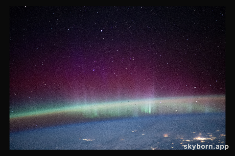 An aurora intersects Earth's airglow beneath a starry sky in this photograph from the International Space Station as it