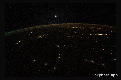 The Moon is pictured above Earth's horizon, its airglow, and an aurora (at far right) in this photograph
