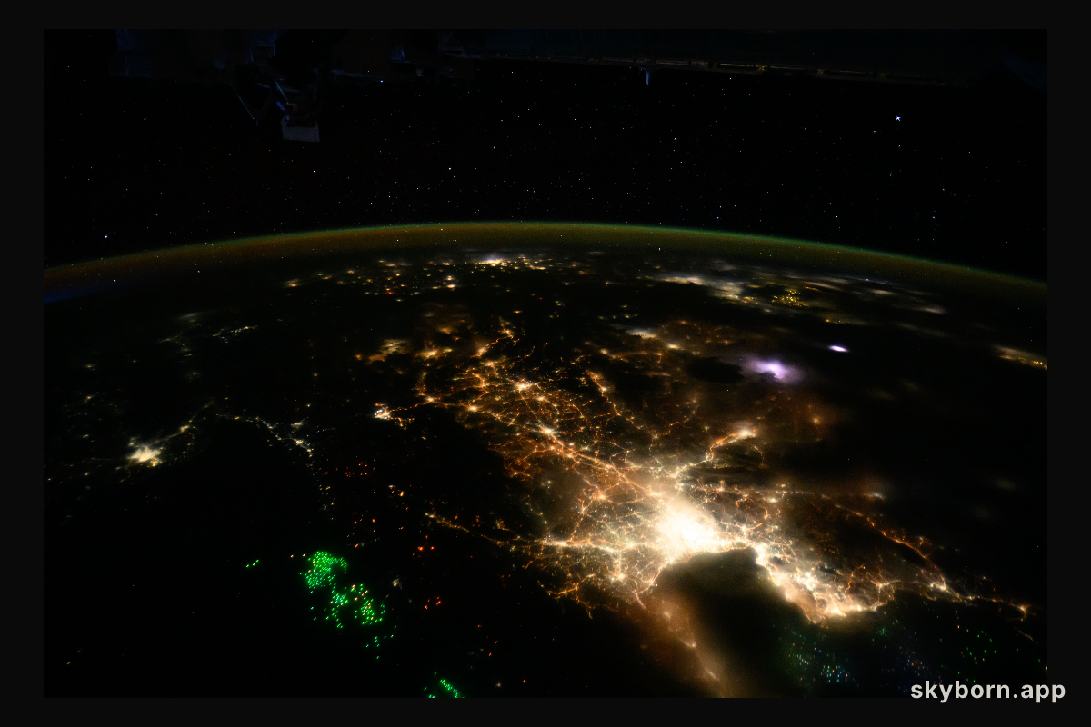 The city lights of Bangkok,Thailand, and its suburbs contrast with the green lights of the fishing boats on the Gulf