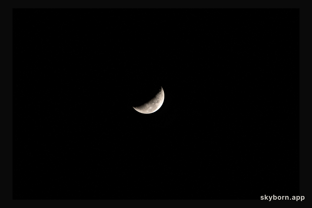 A waning crescent moon hangs against the black of space