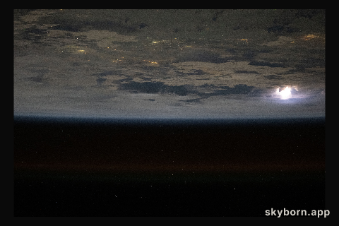 Lightning (at right) illuminates the clouds in this photograph from the International Space Station as it orbited 261