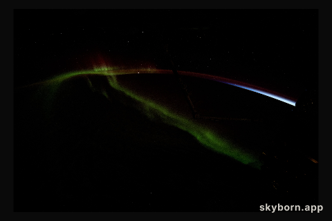 A wispy aurora australis streams over the Earth