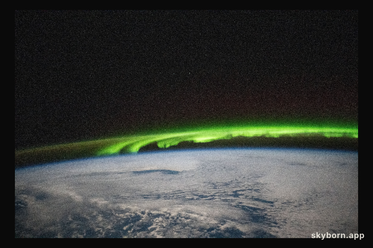 A bright green aurora borealis streams above Earth's surface