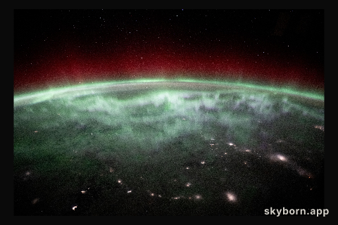 An aurora shimmers and dances above the city lights of Canada