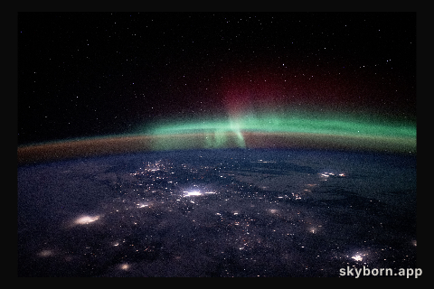 City lights dot the Canadian landscape underneath an aurora