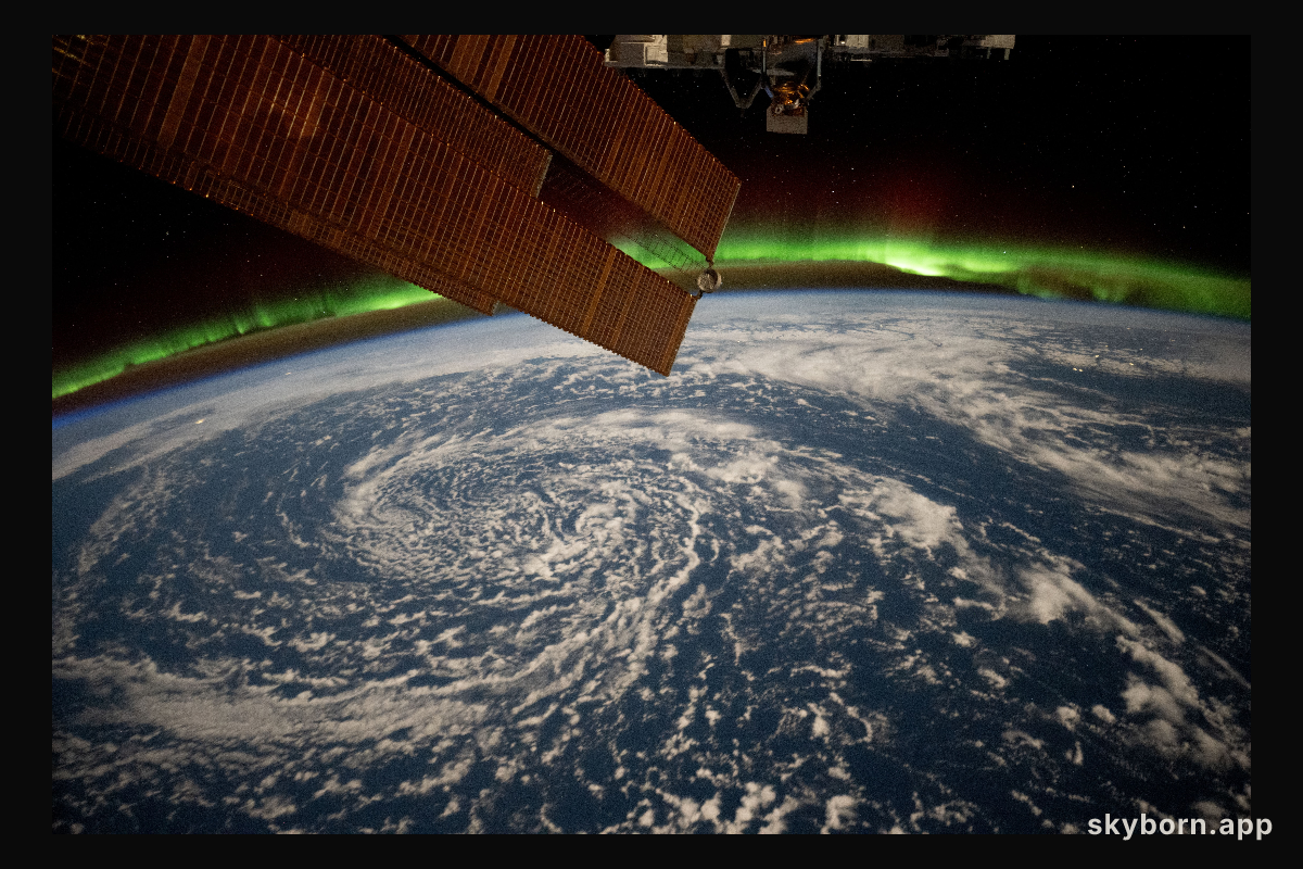 Clouds swirl over the Gulf of Alaska and underneath the aurora borealis