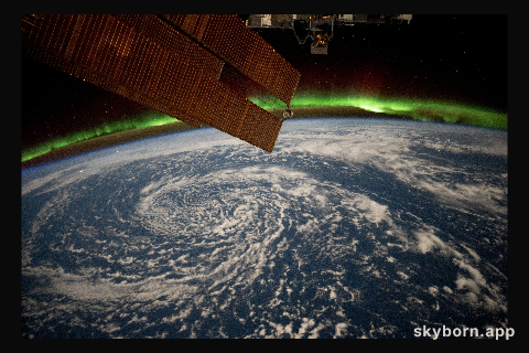 Clouds swirl over the Gulf of Alaska and underneath the aurora borealis