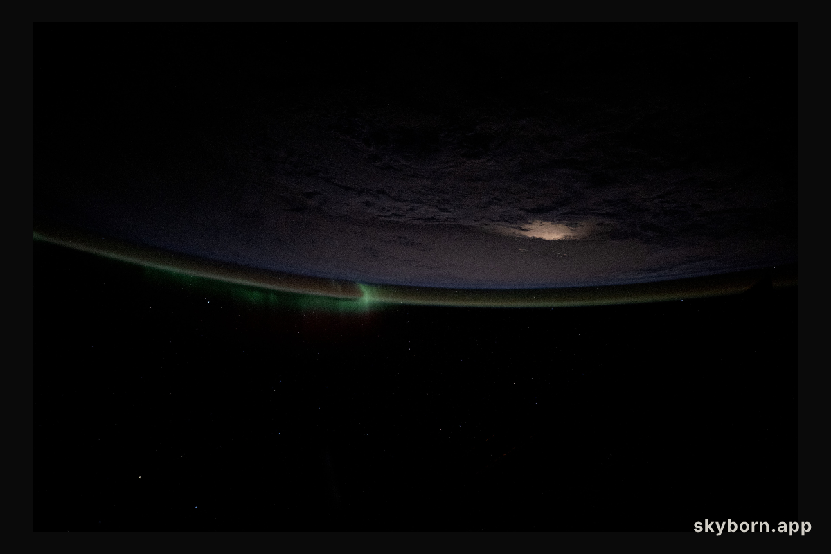 A wispy aurora intersects with Earth's atmospheric glow