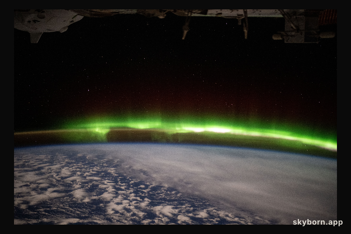 A bright green aurora australis streams above Earth's horizon