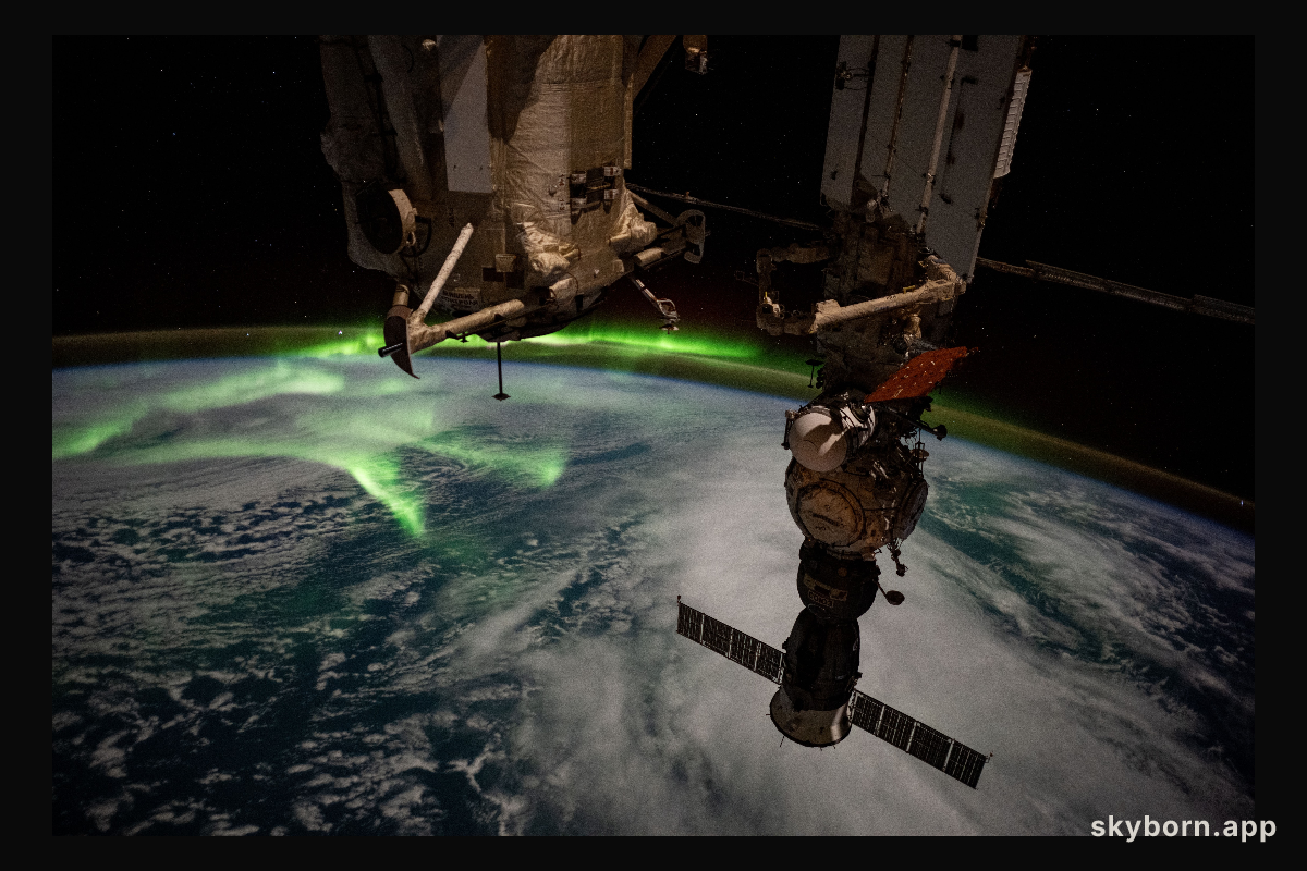 The aurora australis arcs back and forth above a partly cloudy Indian Ocean