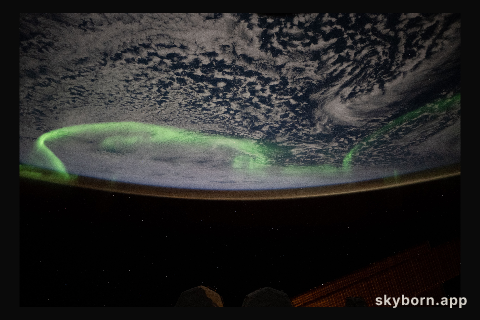 The aurora australis arcs above a partly cloudy Indian Ocean