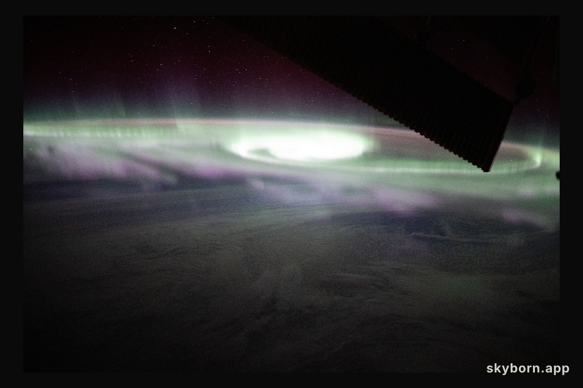 The aurora australis swirls over a cloudy Pacific Ocean