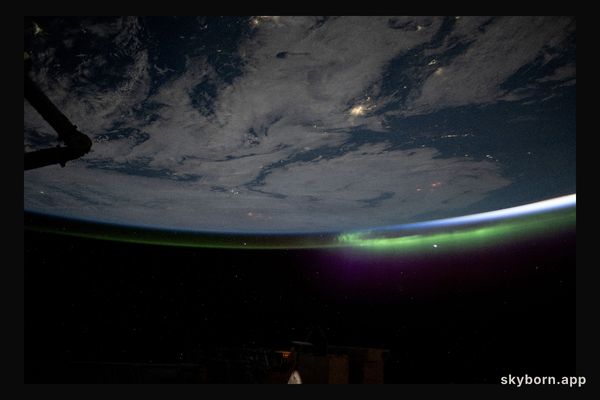 A wispy aurora caps Earth's horizon as an orbital sunrise illuminates the atmosphere