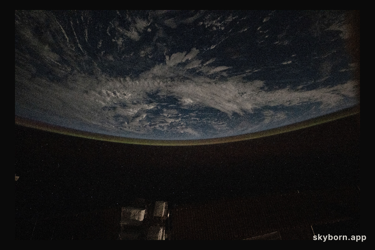 A faint airglow blankets Earth's horizon above the Pacific Ocean