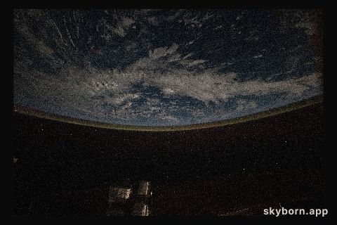 A faint airglow blankets Earth's horizon above the Pacific Ocean