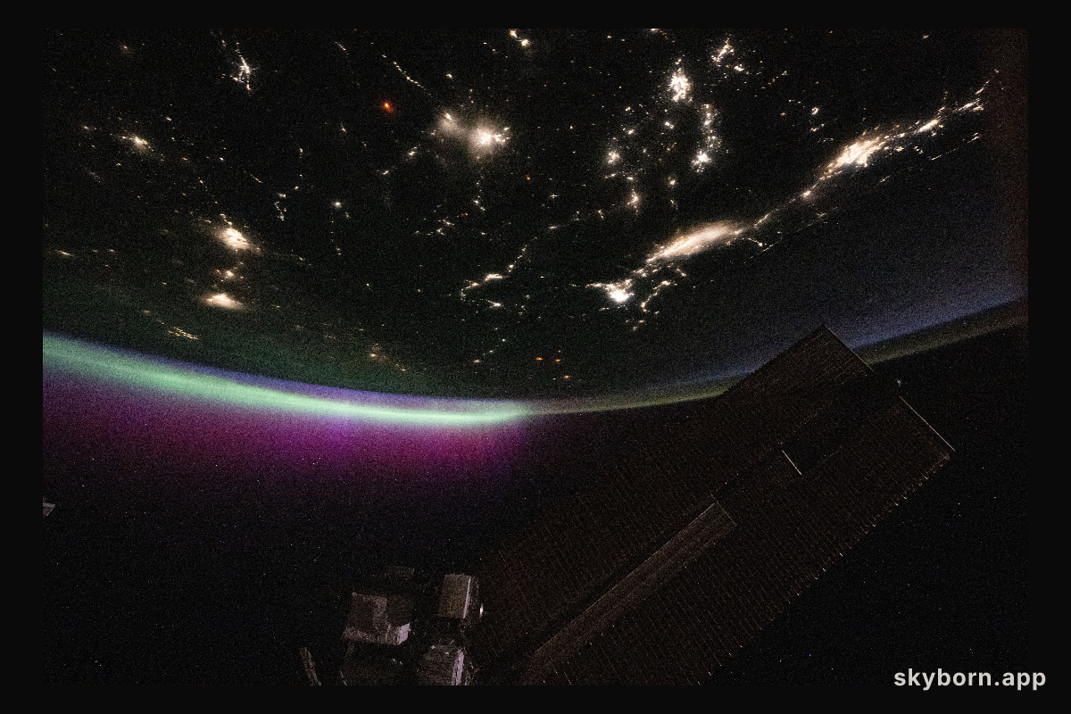 A diffuse aurora glows above Earth's horizon over Canada