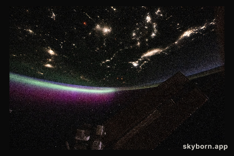 A diffuse aurora glows above Earth's horizon over Canada