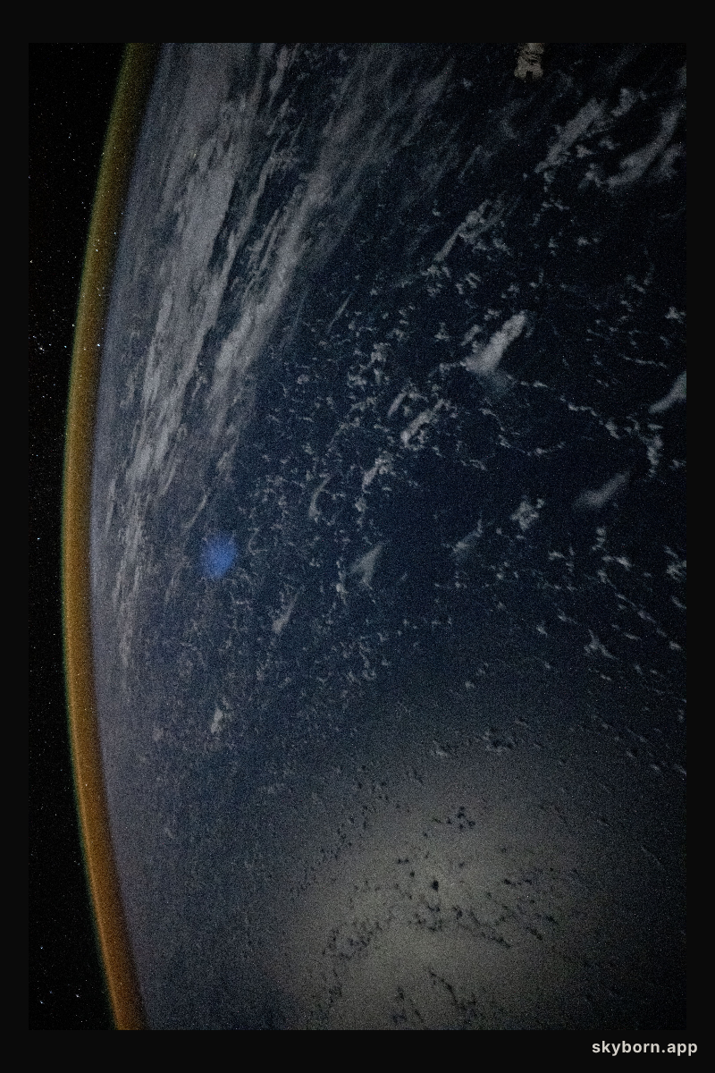 A red-yellow airglow blankets Earth's horizon above the Philippine Sea