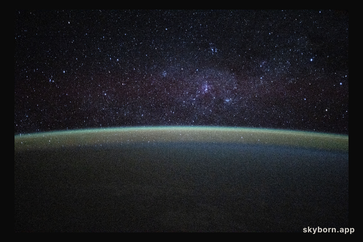 Stars fill the sky above a serene, blue-green airglow blanketing Earth's horizon