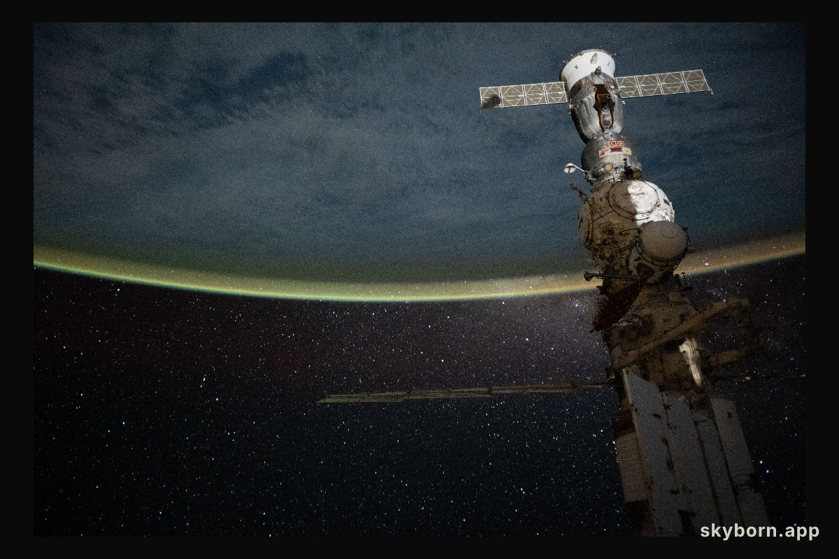 A yellow-green airglow blankets Earth’s horizon beneath a star-filled sky