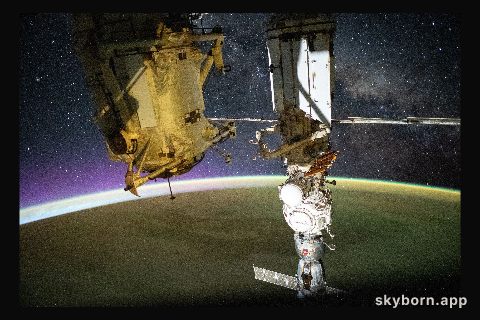 A yellow-green airglow blankets Earth as an orbital sunrise illuminates the planet