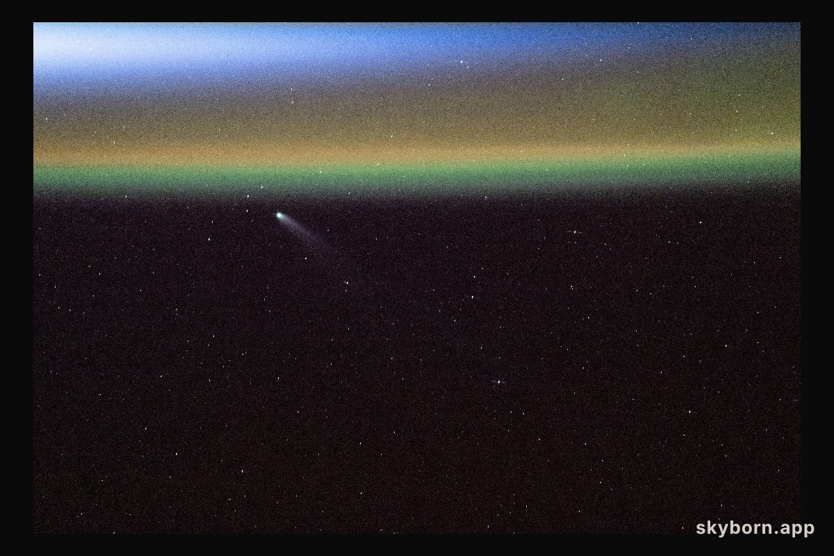 Comet Swan appears above Earth’s yellow-green airglow just before an orbital sunrise