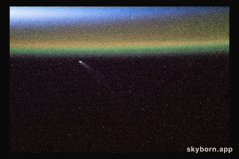 Comet Swan appears above Earth’s yellow-green airglow just before an orbital sunrise