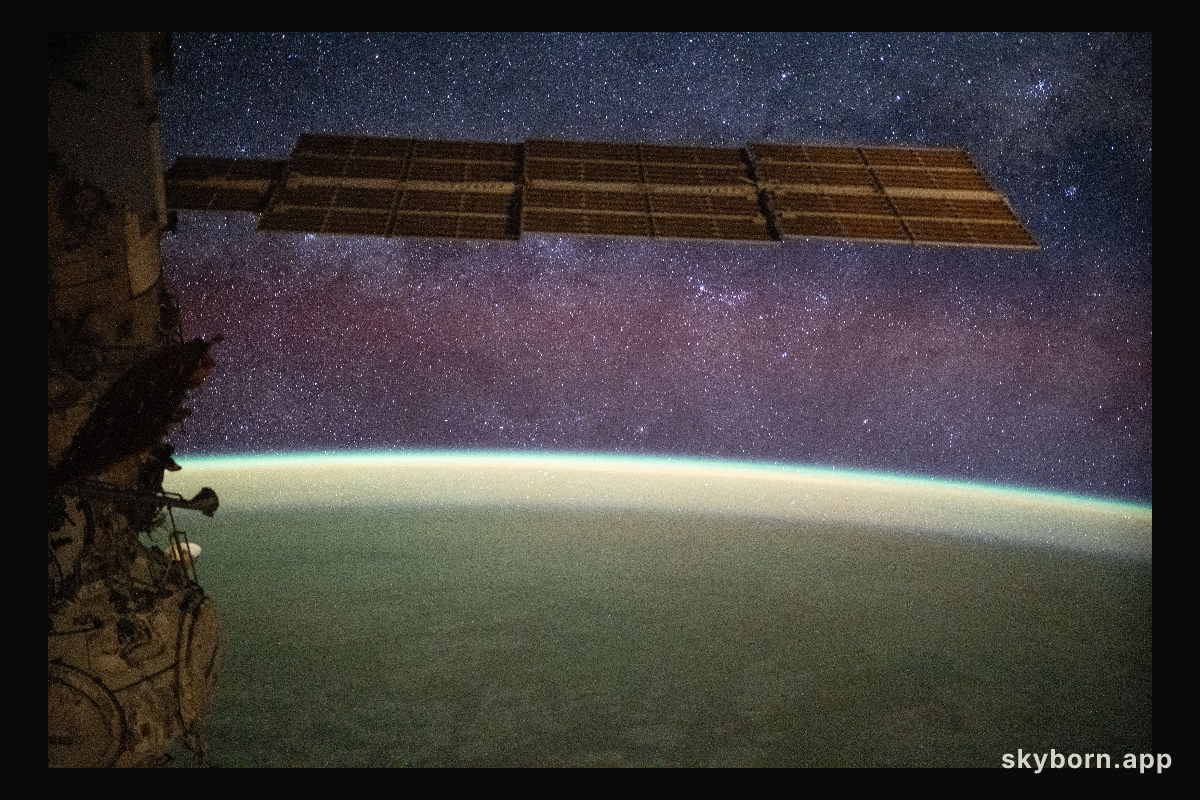 The Milky Way spans the night sky above a yellow-green airglow