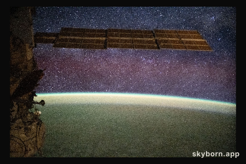 The Milky Way spans the night sky above a yellow-green airglow
