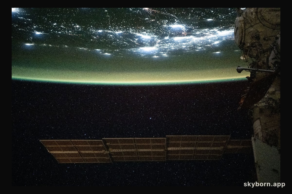 A yellow-green airglow blankets the city lights of North America