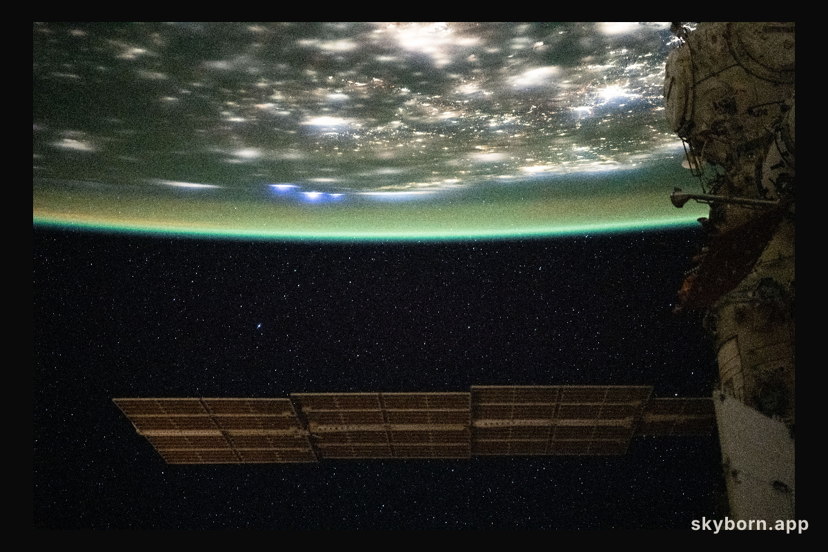 A blue-green airglow blankets the bright city lights of the eastern United States