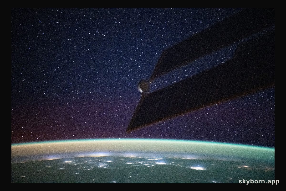 A bright yellow-green airglow blankets Earth's horizon, dotted with the city lights of northern India, beneath