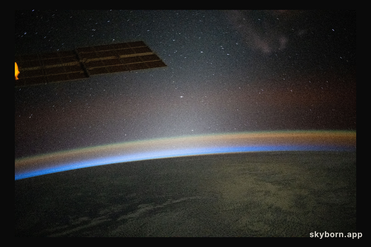 A red-yellow airglow blankets Earth as the last rays of an orbital sunset illuminate the atmosphere