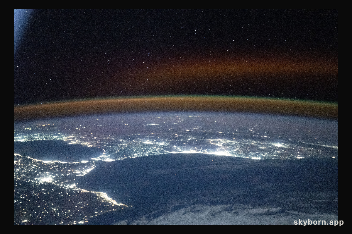 A red-yellow airglow blankets Earth's horizon above southwestern Europe and North Africa